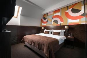 利沃夫BANKHOTEL的酒店客房设有一张床,墙上挂有绘画作品