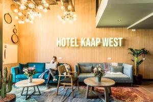 韦斯特卡佩勒Hotel Kaap West I Kloeg Collection的坐在酒店外的卡普西大厅沙发上的女人