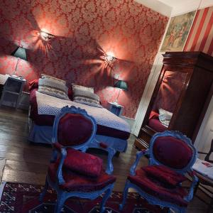 杜埃Chambres d'Hôtes Les Foulons的一间卧室配有一张红色墙壁的床和两把椅子