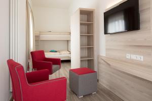里德林根Hotel Gudrun的客厅配有2把红色椅子和电视