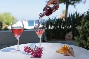 斯基罗斯岛Skyros Ammos Hotel的把酒倒进餐桌上的玻璃杯里的人