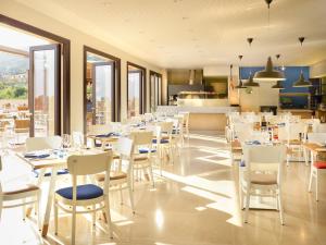 切法卢Hapimag Resort Cefalù的一间带白色桌椅的餐厅和一间厨房