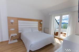 桑亨霍那宁海滩Spa酒店的卧室设有白色的床和大窗户