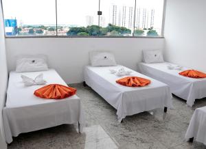戈亚尼亚Hotel Cco Goiânia的带3张床和橙色床单的客房