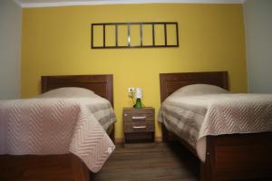 波托西Los Faroles Hostal的一间卧室配有两张床和一张带台灯的桌子