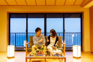恩纳冲绳海之旅亭日式旅馆的两人坐在桌子房间里椅子上