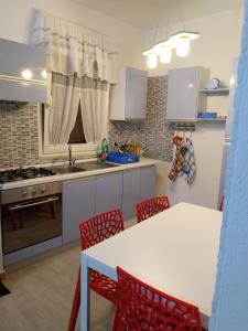 坎波马里诺Rosa dei Venti house的厨房配有红色的椅子和白色的桌子