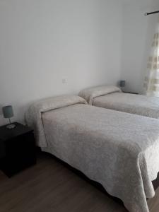 贝纳尔马德纳贝纳尔海滩茉莉公寓的配有白色墙壁和木地板的客房内的两张床
