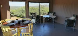 MaanhaarrandShamba Yetu Mountain Lodge的配有大窗户的客房内的桌椅