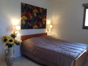 CaseneuveLe bastidon du Luberon的卧室配有一张床,墙上挂有绘画作品
