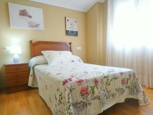 利洛La Casa Periquita的一间卧室配有一张带花卉床罩的床和窗户。