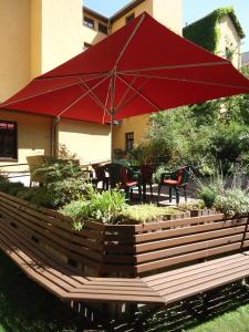 萨勒河畔哈雷玛莎酒店的一个带红色遮阳伞和桌椅的庭院