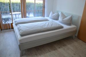 阿尔高内的伊门施塔特Ferienwohnung Emil的一张带白色床单和枕头的床