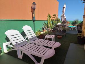圣克鲁斯-德特内里费8 Calle Tangara La gloria的两把白色椅子坐在种有植物的庭院里