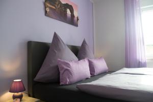 贝恩堡Zimmervermietung Hebenstreit的一间卧室配有一张带紫色枕头的床和窗户。