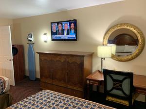 莫纳汉斯Texan Inn and Suites Monahans的酒店客房设有一张床和墙上的电视