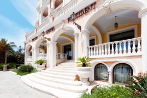 奥尔比亚总统大酒店的一座白色的大建筑,有楼梯和盆栽植物