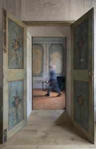 曼托瓦Appartamento affrescato 180mq in palazzo del 600 a Mantova的穿过墙上画作的房间的人