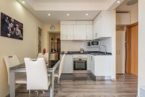 丰沙尔America Apartment by HR Madeira的厨房配有白色橱柜和桌椅