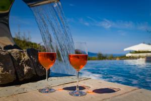 马萨鲁布朗斯奥勒姆乡村民宿的两杯葡萄酒坐在游泳池旁
