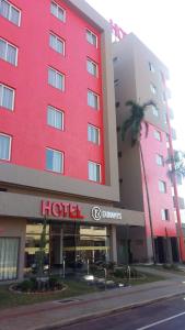 隆德里纳Dunamys Hotel Londrina的一间红色的酒店,前面有棕榈树