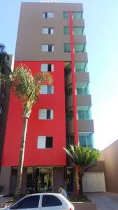 隆德里纳Dunamys Hotel Londrina的一座红色的建筑,前面有棕榈树