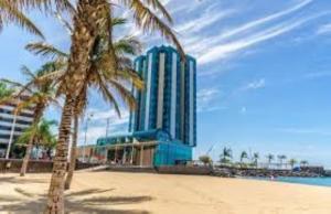 阿雷西费Piso Arrecife Centro A的海滩上的蓝色建筑,种有棕榈树