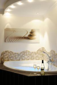 恩斯特温尼贝格霍夫酒店的一间带浴缸和两杯酒的浴室