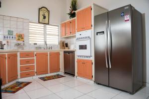 Upper Princeʼs QuarterVilla Fleur De Mer Sint Maarten的厨房配有不锈钢冰箱和橙色橱柜