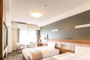 大阪Comfort Hotel Shin-Osaka的酒店客房设有两张床和一张桌子。
