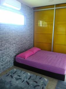 卢穆特Yellow Cube at Lumut Cube Homestay Kontena的一间卧室配有紫色的床和砖墙