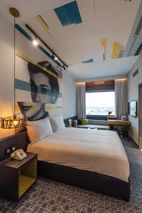 迪拜Studio One Hotel的酒店客房设有一张大床,墙上挂有绘画作品