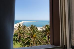 特拉尼Palazzo Filisio - Regia Restaurant的享有棕榈树海滩和大海美景的窗户