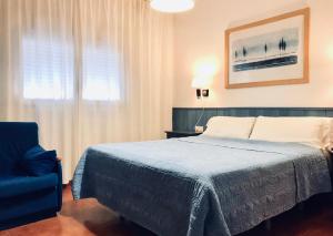 蓬塔翁布里亚普拉亚旅馆的一间卧室配有一张床和一张蓝色椅子