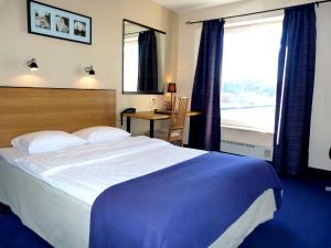 乌德瓦拉滨江酒店的一间卧室配有一张大床、一张书桌和一个窗户。