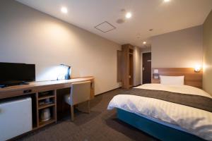 和歌山HOTEL CITY INN WAKAYAMA Wakayama-Ekimae的酒店客房配有一张床和一张书桌及一台电视