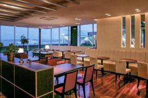 常滑市中央国际机场康福特茵酒店的餐厅设有桌椅和大窗户。