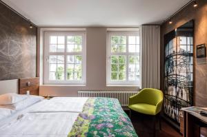 埃森埃森米乔普斯塔特酒店的一间卧室配有一张床和一把绿色椅子