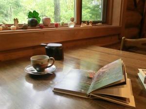 安昙野市Canadian Loghouse Inn AzuminoYujin的木桌上的书,带杯和咖啡杯