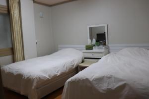 济州市奥拉星汽车旅馆的两张位于酒店客房的床,配有镜子和一张四面 ⁇ 