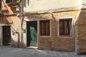 威尼斯Palazzetto Canossa的一座古老的砖砌建筑,设有绿门和窗户