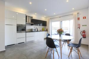 巴勒尔Vitamin Sea, The Terrace Apartment的厨房配有白色橱柜和桌椅