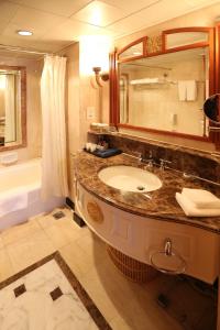 青岛青岛汇泉王朝大饭店的浴室配有盥洗盆、镜子和浴缸