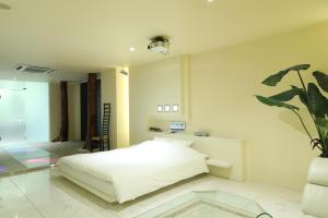 札幌C-HOTEL affetto(Adult Only)的卧室配有白色的床和盆栽植物