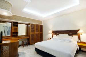 库塔巴厘别墅酒店的一间卧室配有一张床、一张书桌和一台电视