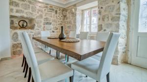帕里斯特Beachfront Villa Perast的一间带木桌和白色椅子的用餐室