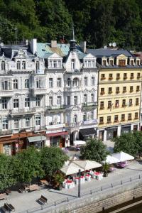 卡罗维发利帕拉茨基酒店的一座白色的大建筑,前面设有桌椅