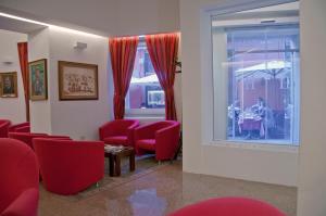 卡利亚里意大利酒店的一间设有红色椅子、桌子和窗户的等候室