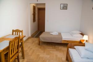 克拉科夫圣西蒙大教堂民宿的一间设有两张床和一张桌子及椅子的房间
