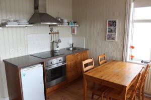 侯尔马维克Steinhúsið的厨房配有桌子、炉灶和水槽。
